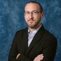 Headshot of Professor Parker. A man with light brown hair and blue eyes