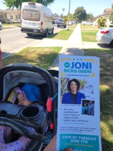 Baby in stroller on sidewalk with a campaign flyer.