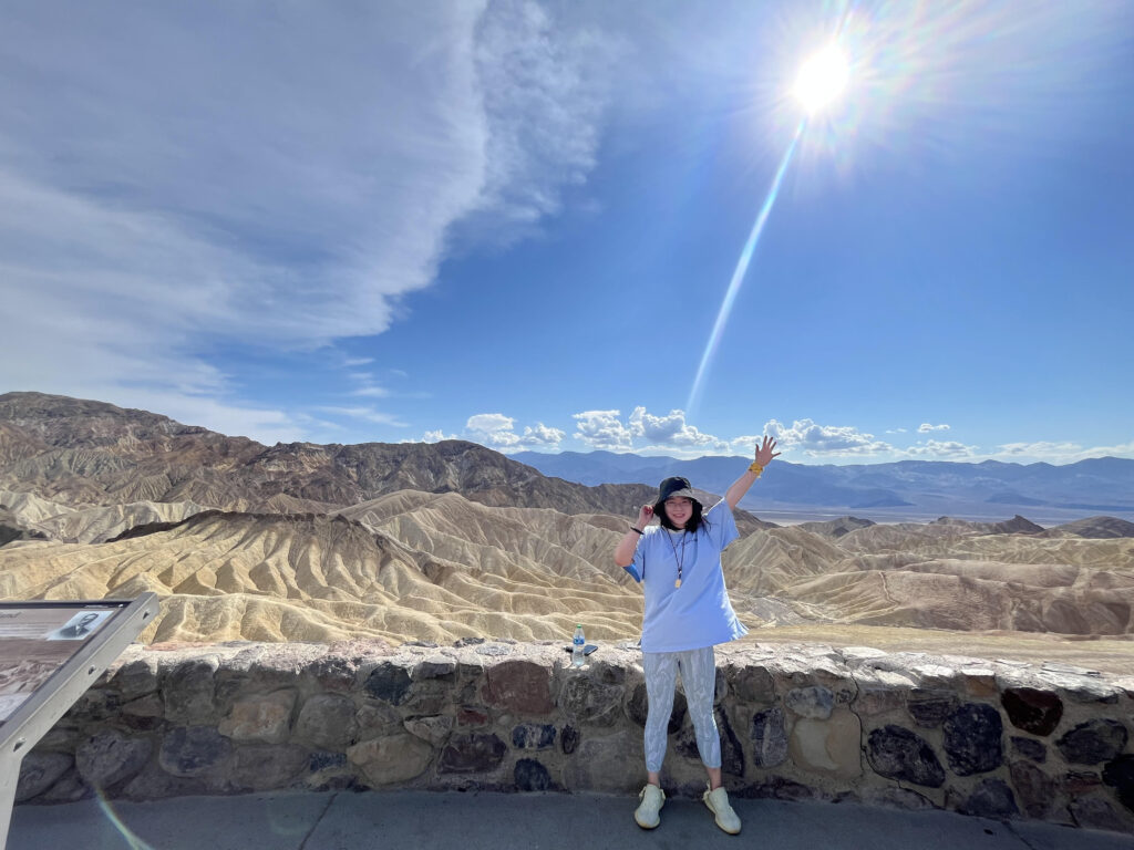 Hengrui Cai standing and waving, with desert hills in the background.